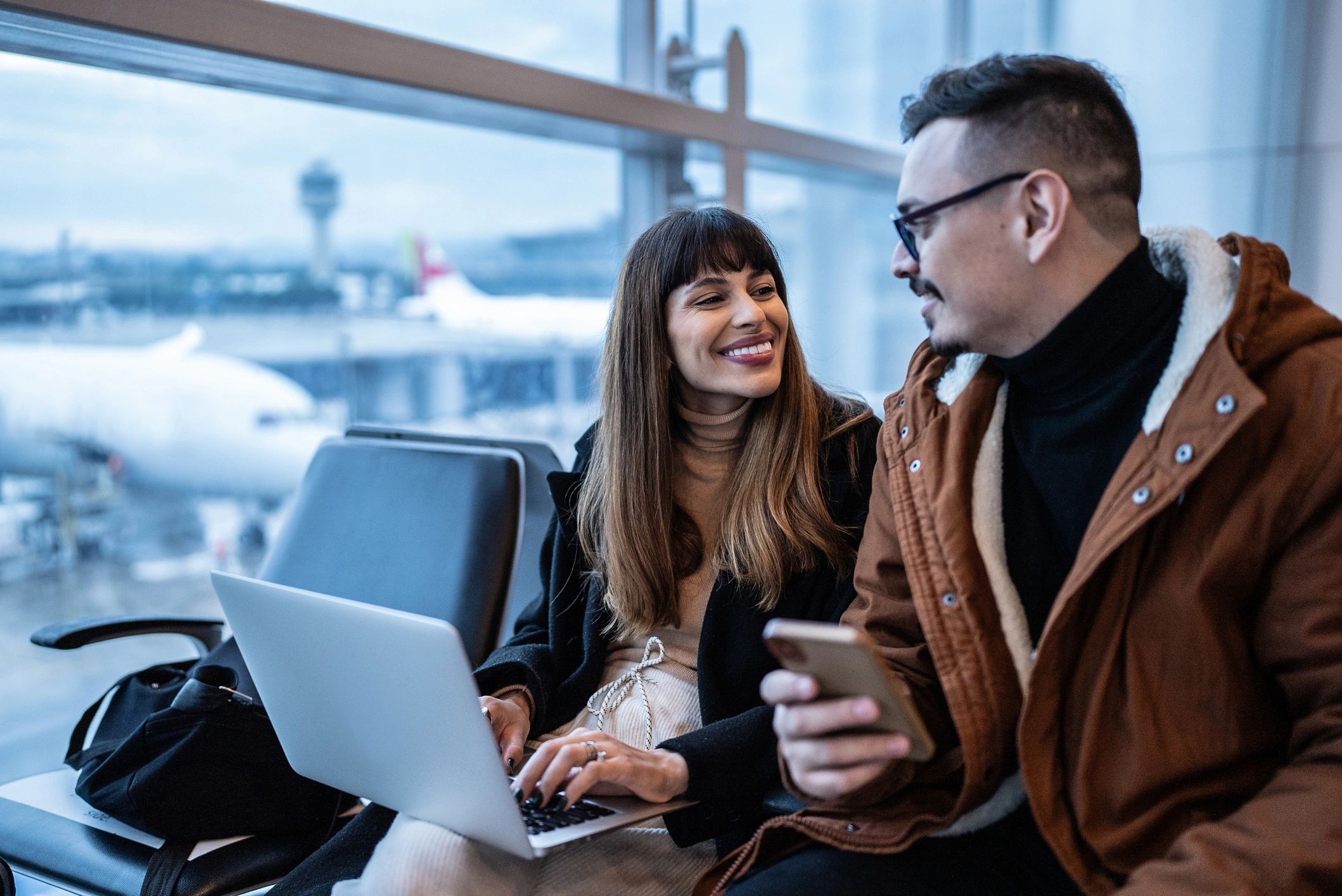 Travelers using devices at the airport while planning a trip