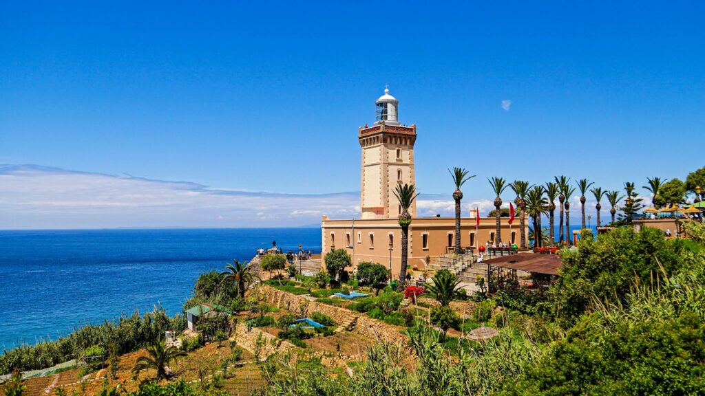 Daylight view of Cape Spartel Lighthouse surrounded by palm trees and gardens, located on the promontory where the Atlantic Ocean meets the Mediterranean Sea, Historic maritime landmark and travel destination in Tangier, Morocco